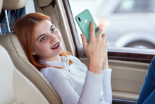 Young Redhead Woman Driver Taking Selfies With Her Mobile Phone Sitting Behind The Wheel Of The Car In Rush Hour Traffic Jam.