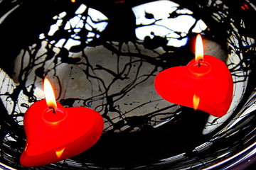 Two red candles in water with black and white abstract background Valentines day concept.