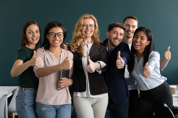 Wall Mural - Interns and aged ceo looking at camera showing thumbs up