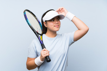 Wall Mural - Young teenager Asian girl playing tennis having doubts and with confuse face expression