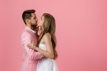 Wall Mural - happy couple in love embracing on pink background. man in a jacket and a woman in a dress are happy together. st valentines day. copy space