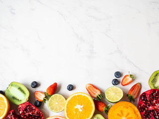 Wall Mural - Multicolored seasonal healthy natural fruit border with persimmon, blueberries, orange, kiwi, strawberries, grapefruit, pomegranate, orange slices.