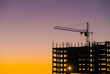 Industrial machinery and the construction crane. Cranes and skyscraper under construction, city skyline at sunset, sunrise Building under Construction site.