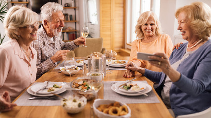 Happy senior friends having fun while having lunch together at home.