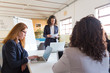 © Mangostar - Professional businesswomen during presentation in office. Serious businesswoman standing with papers and female colleagues using laptops in office. Women in business concept