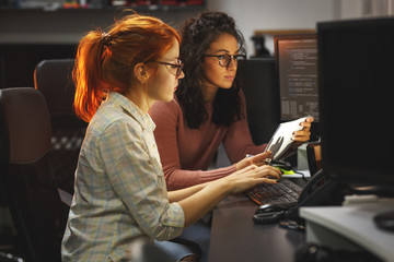 	 Two female programmers working on new project.They working late at night at the office.	