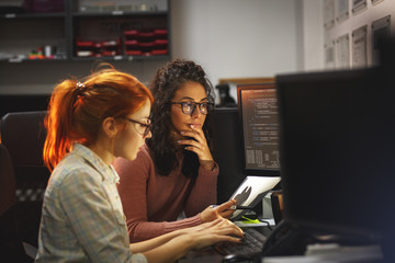 	 Two female programmers working on new project.They working late at night at the office.	