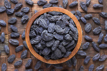 blue raisins, dried grapes in wooden bowl, top view.