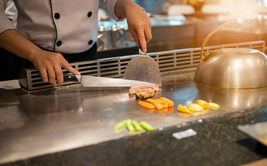 Japanese chef cooking meat in teppanyaki restaurant