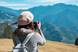 © Kittiphan - Young woman traveler taking a picture of beautiful landscape