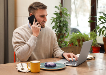 Wall Mural - Male blogger talking on phone in cafe