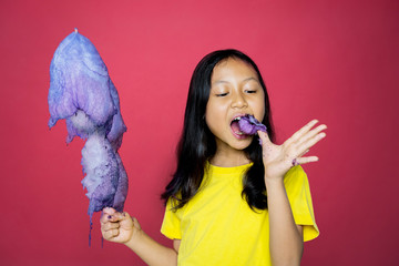 Wall Mural - Girl holding a candy while eating the ripped part