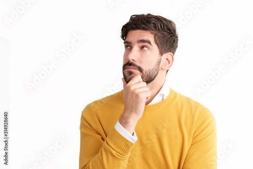 Fotomural Handsome young man looking thoughtfully at isolated white background with copy s