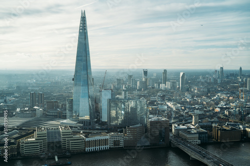 Aerial view of London with The Shard skyscraper and Thames river at sunset with grey clouds in the sky. Financial district in the center of London from the viewing platform at Sky Garden.