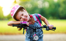 Happy Cheerful Child Girl Riding A Bike In Park In Nature.