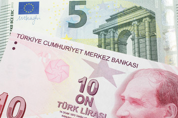 A red ten Turkish lira bill close up in macro with a red, European five Euro note 