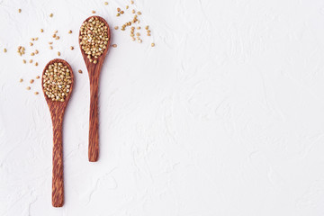 Buckwheat green and plain on a white background, top view two wooden spoons. Copy space