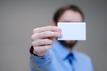 Young business man holding white business card on modern office blur background