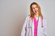 © Krakenimages.com - Redhead caucasian doctor woman wearing pink stethoscope over isolated background sticking tongue out happy with funny expression. Emotion concept.
