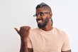© Krakenimages.com - African american man wearing striped t-shirt and glasses over isolated white background smiling with happy face looking and pointing to the side with thumb up.