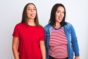 Wall Mural - Young beautiful women wearing casual clothes standing over isolated white background sticking tongue out happy with funny expression. Emotion concept.