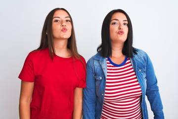 Poster - Young beautiful women wearing casual clothes standing over isolated white background looking at the camera blowing a kiss on air being lovely and sexy. Love expression.