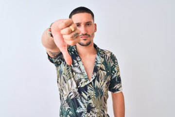 Poster - Young handsome man wearing Hawaiian summer shirt over isolated background looking unhappy and angry showing rejection and negative with thumbs down gesture. Bad expression.