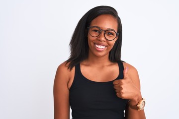 Beautiful young african american woman wearing glasses over isolated background doing happy thumbs up gesture with hand. Approving expression looking at the camera with showing success.