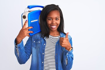 Young african american woman holding vintage retro radio over isolated background happy with big smile doing ok sign, thumb up with fingers, excellent sign