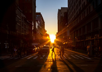 Wall Mural - Crowds of people walk through the busy intersection at 23rd Street and Fifth Avenue in New York City with the bright light of sunset