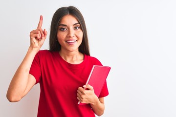Wall Mural - Young beautiful student woman holding red book standing over isolated white background surprised with an idea or question pointing finger with happy face, number one