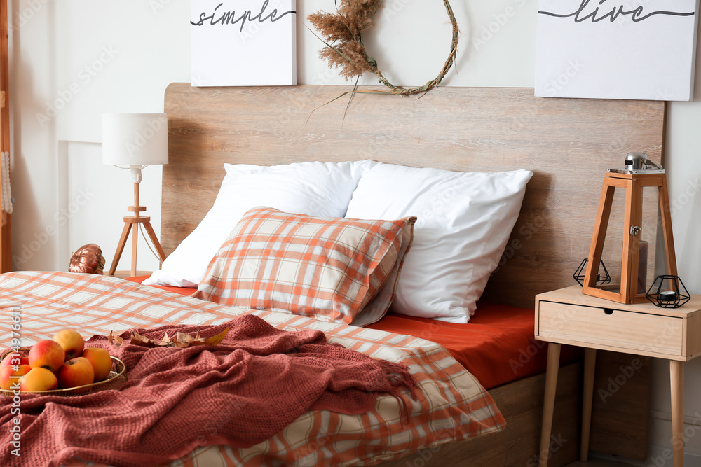Big comfortable bed in stylish interior of room with autumn decor