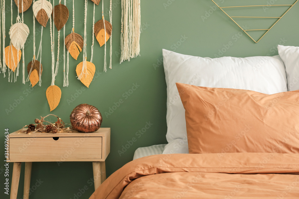 Big comfortable bed in stylish interior of room with autumn decor