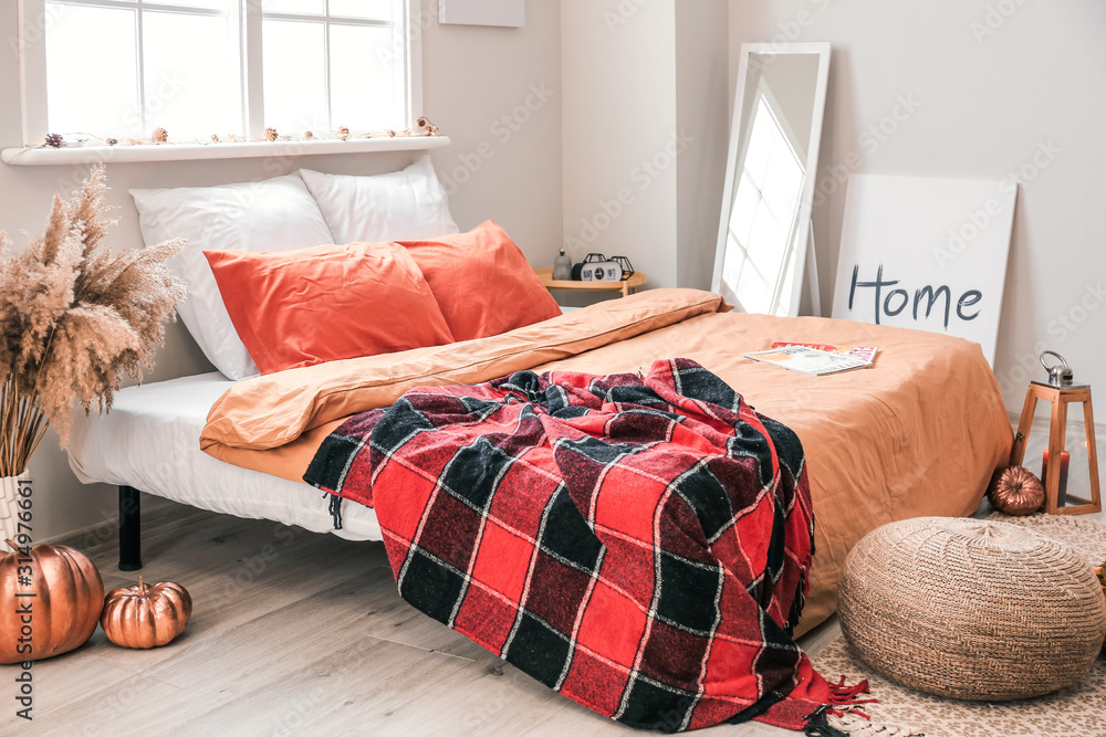 Stylish interior of room with big comfortable bed and autumn decor