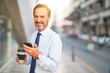© Krakenimages.com - Middle age handsome businessman using smartphone drinking take away coffee smiling