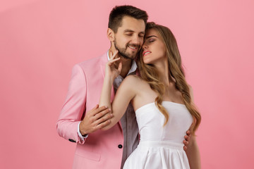 Wall Mural - happy couple in love embracing on pink background. man in a jacket and a woman in a dress are happy together. st valentines day.