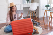 © weedezign - Young asian woman traveler prepare cloth and stuff into orange suitcase for holiday vacation at home.backpacker travel concept