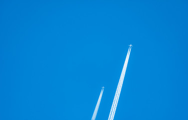 Two airplane with white condensation tracks. Jet plane on clear blue sky with vapor trail. Travel by aeroplane concept. Trails of exhaust gas from airplane engine. Aircraft with white stripes.