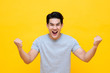 Portrait of cheerful young Asian man raising his fists