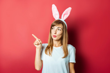 Young beautiful woman with rabbit ears on a pink background. Easter concept