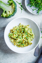 Canvas Print - Green risotto with broccoli, green peas and sprouts in white plate, top view. Healthy vegan food concept.