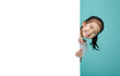 © DN6 - Smiling happy cute child hiding behind a blank white board, empty space in studio shot isolated on colorful blue background