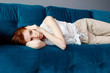 © Dmitrii Kotin - Young woman lying on couch and suffering from headache at home.