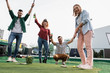© Zoran Zeremski - Group of smiling friends enjoying together playing mini golf in the city.