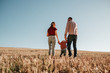 © Romvy - Happy Young Family Mom and Dad with Their Little Son Enjoying Summer Weekend Picnic Outside the City in the Field at Sunny Day Sunset, Vacation Time Concept