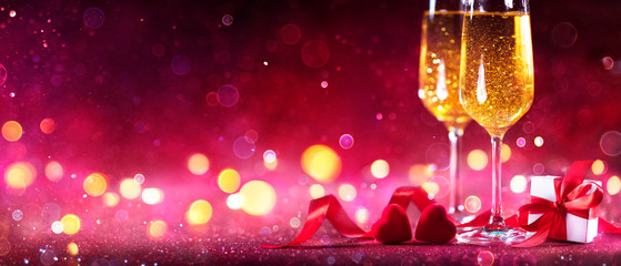 Wall Mural - valentines celebration with champagne - flutes with defocused lights in red shiny background