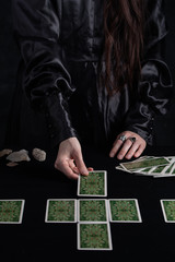 Female tells the future with playing cards. Tarot card concept on the table. Prediction of the future. Fortuneteller hands in black vestments.Psychic.