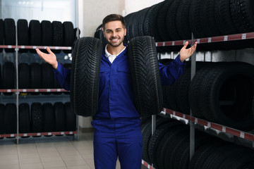 Poster - Male mechanic with car tires in auto store