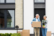 © LIGHTFIELD STUDIOS - smiling man holding box and woman holding plant near new house