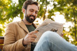 © Drobot Dean - Image of handsome adult man reading newspaper on bench in park